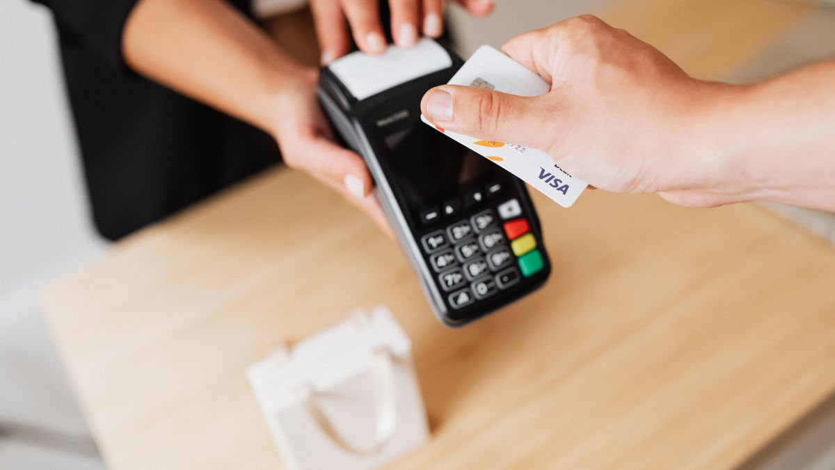 Customer tapping a card on a card machine at a shop counter