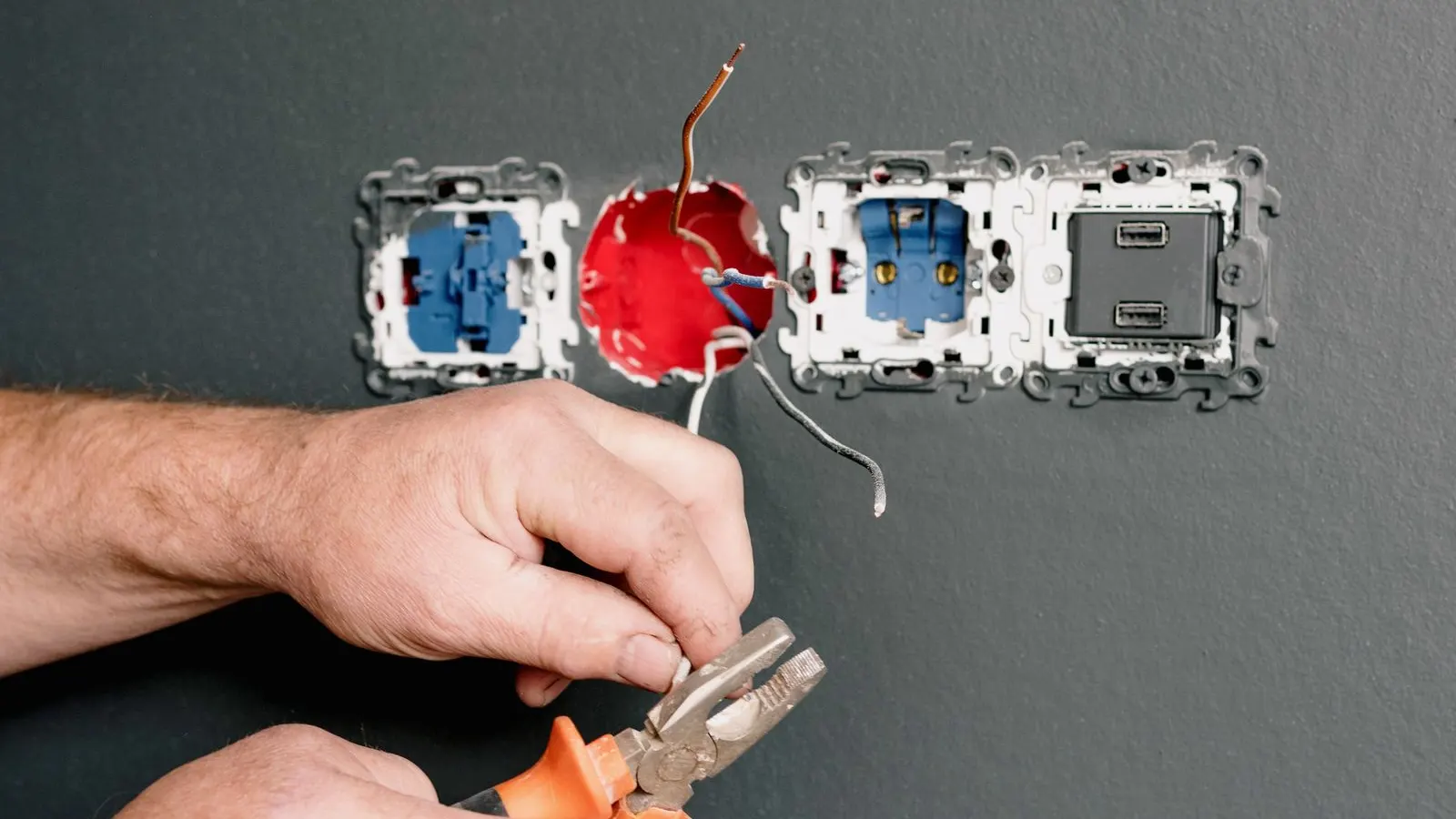Electrician repairing a socket with pliers