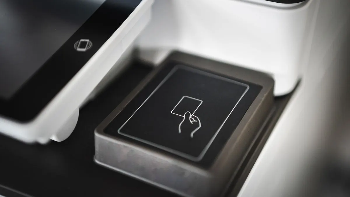 A card machine and cash on a counter, weighing up card versus cash