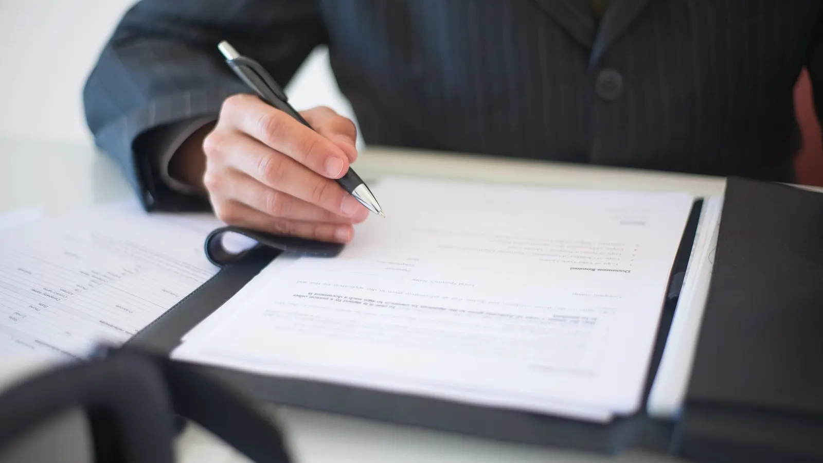 Close-up of a hand signing a contract document