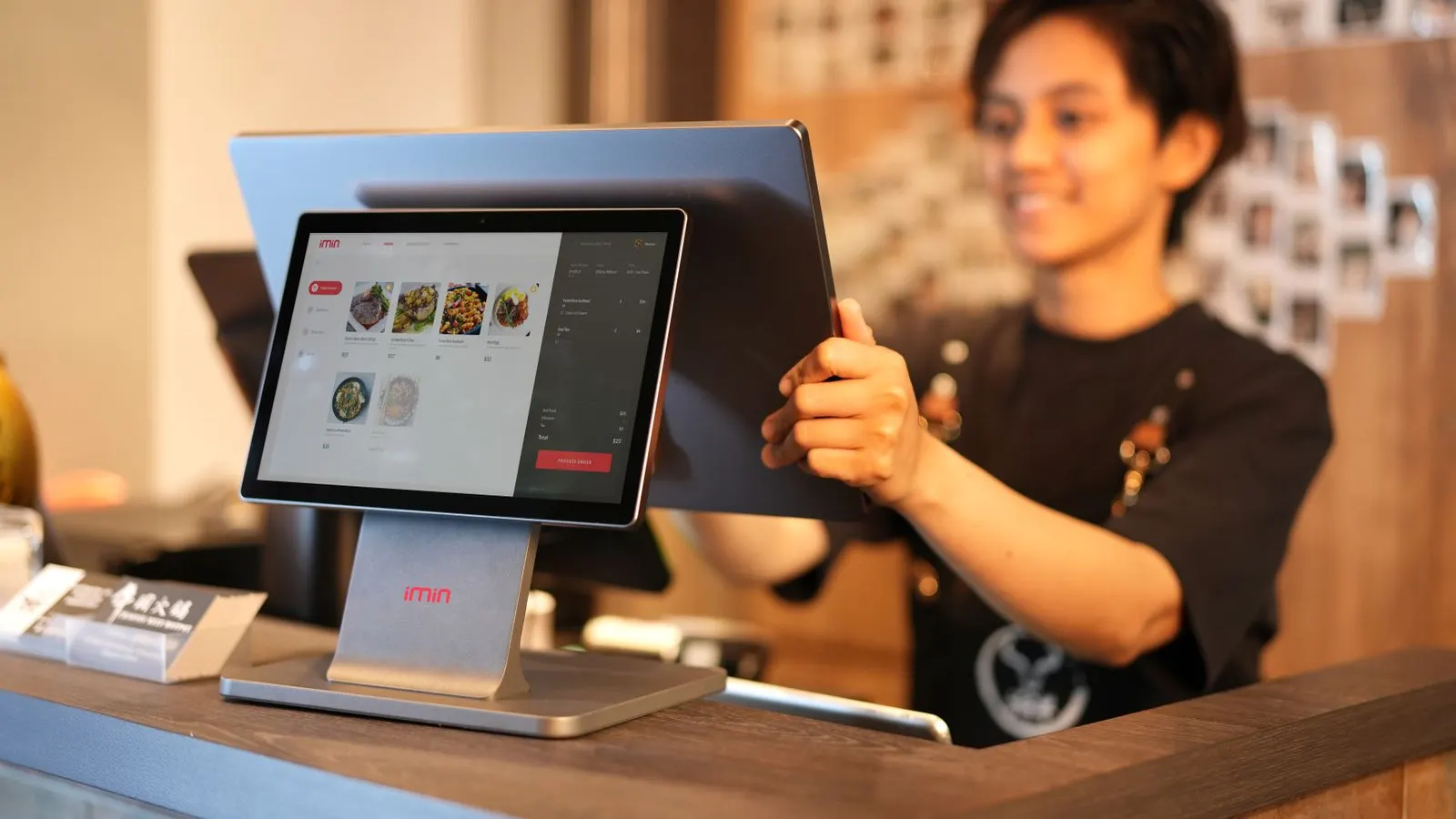 Cashier setting up a touchscreen EPOS till on a shop counter