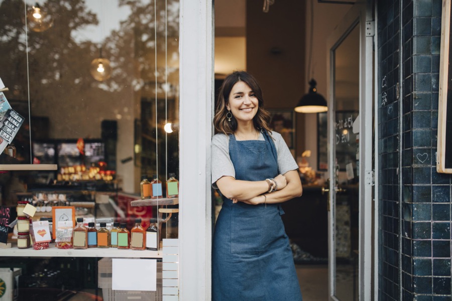 Independent café and deli owner in her shop doorway